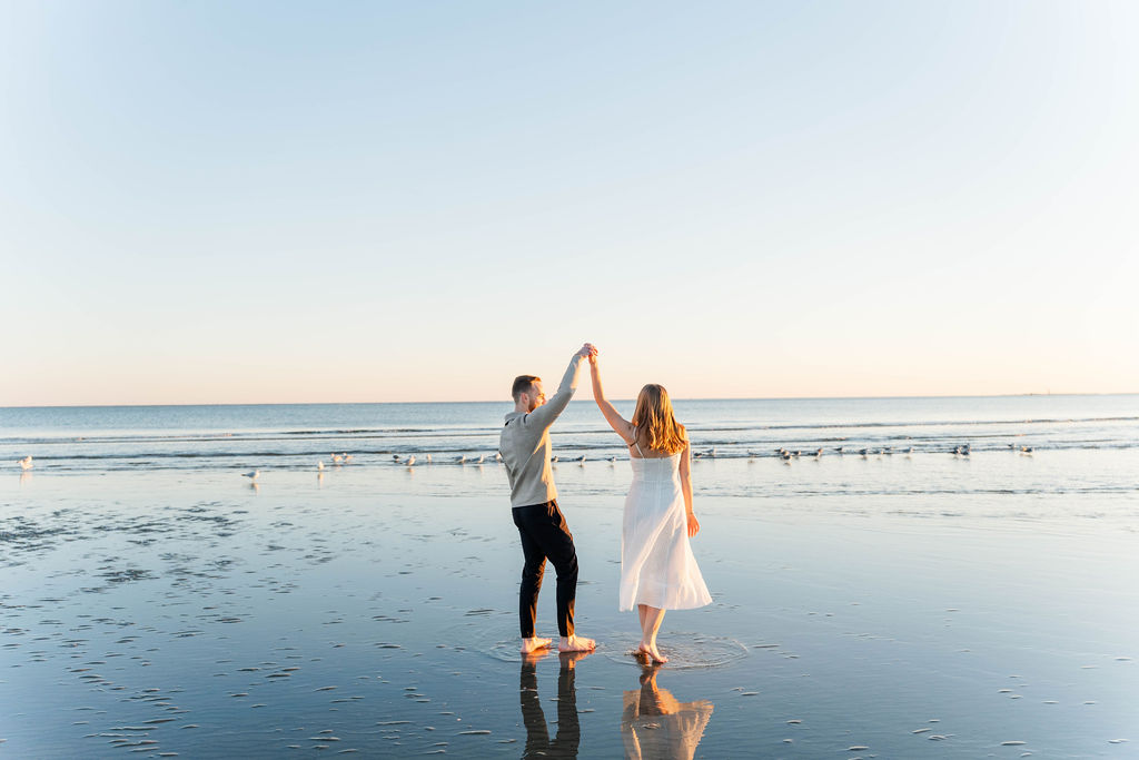 Windy Charleston beach engagement session with a couple walking along the shoreline
