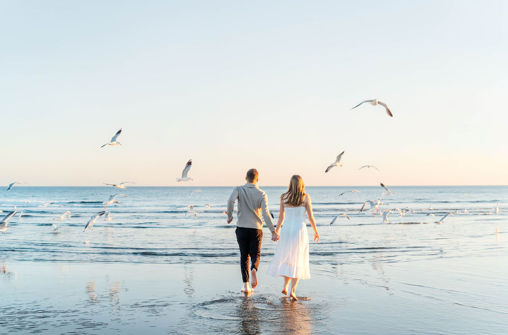 Caroline and Jamie running through seagulls during their Sullivan’s Island engagement photos near Charleston