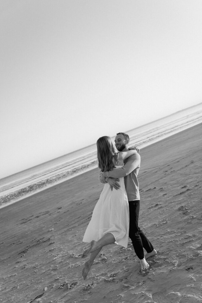 Joyful beach engagement photos of a couple running together along the Charleston coastline
