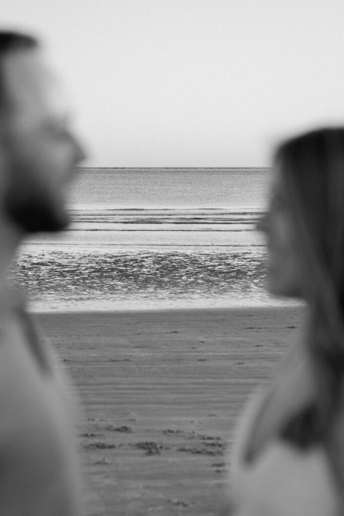 Couple holding hands and walking toward the ocean during Charleston beach engagement photos
